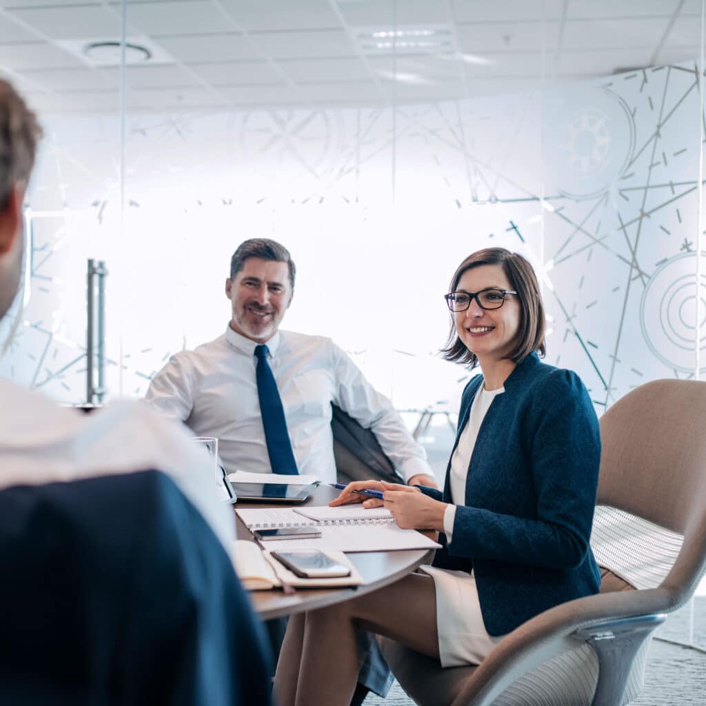 Drei Personen beraten in einem eleganten Besprechungsraum die digitale Strategie des Unternehmens.